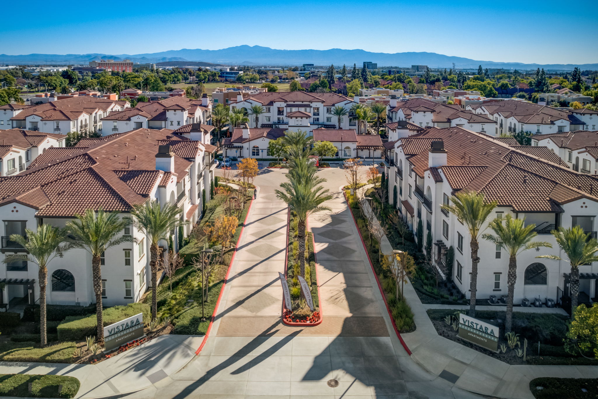 Welcome to Vistara Apartments in Ontario, CA – Aerial view of the community entrance with palm trees.